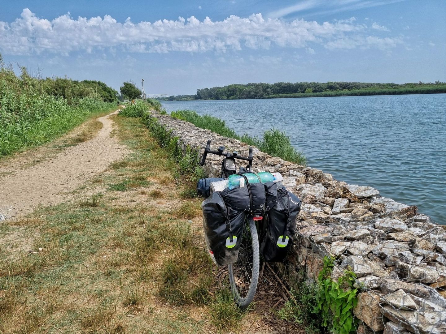 Vélo chargé de sacoches sur un chemin au bord d’une rivière